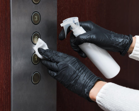 hands with gloves disinfecting elevator buttons. High quality and resolution beautiful photo concept