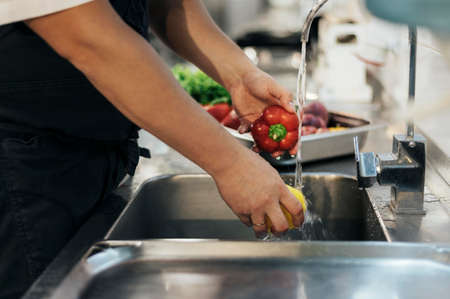 side view male chef washing vegetablesの写真素材