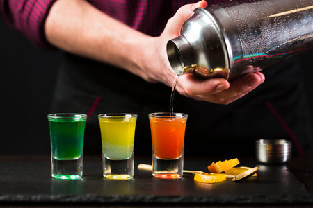 front view man pouring cocktail shot glasses