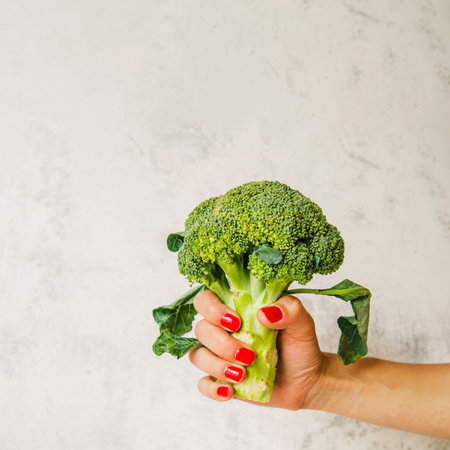 raw broccoli woman s hand white wall backgroundの写真素材