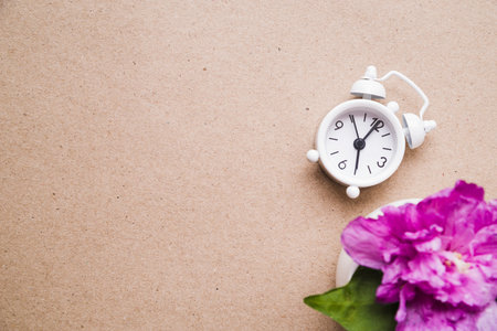 pink peony flower vase with white alarm clock paper texture cardboard background