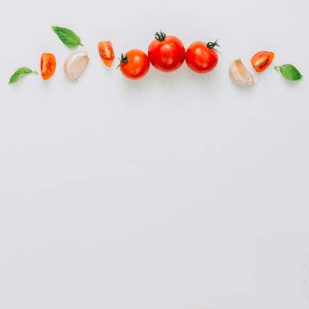 whole slice cherry tomatoes garlic clove basil white backgroundの写真素材