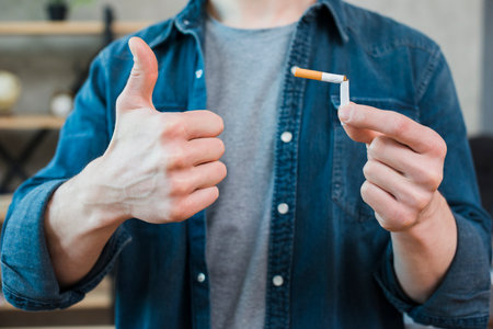 man holding broken cigarette showing thumb up gestureの写真素材