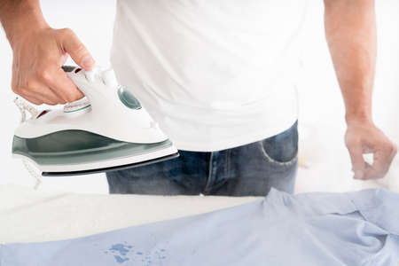 man steaming clothes with clothing ironの写真素材