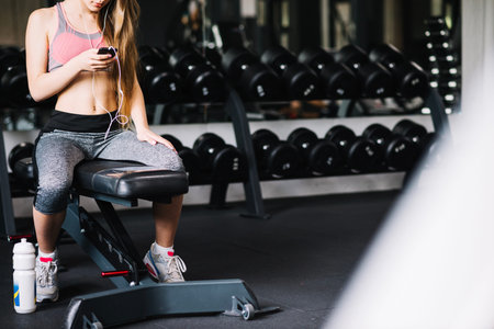 girl with phone sitting gym