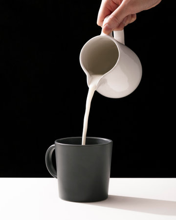 front view hand pouring milk into mugの写真素材