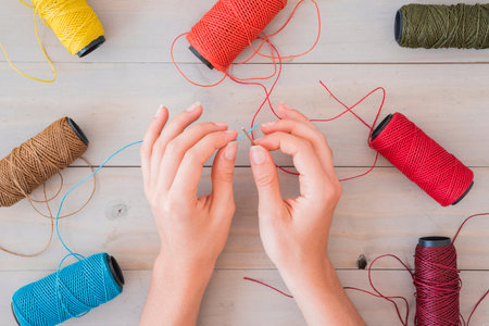 woman s hand inserting blue yarn needle wooden table