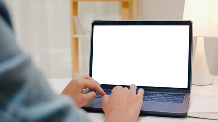 Creative young asia woman sitting at Her desk using laptop with mock up white screen in the cozy...