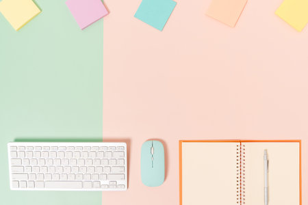 Creative flat lay photo of workspace desk. Top view office desk with keyboard, mouse and open mockup black notebook on pastel green pink color background. Top view mock up with copy space photography.の写真素材