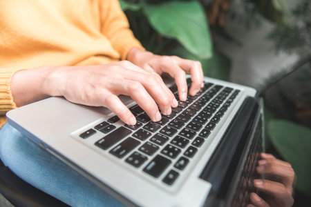 Close up young woman shopping online with her laptop in a coffee shop garden with a background of a...
