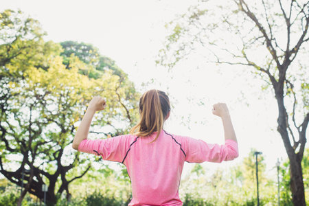 Asian young woman warm up the body stretching before morning exercise and yoga in the park under warm light morning. Healthy young asian woman exercising at park. Woman exercise outdoor concept.の写真素材