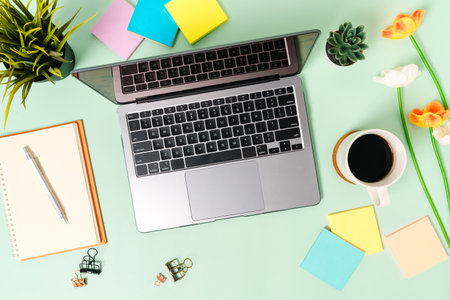 Creative flat lay photo of workspace desk. Top view office desk with laptop, coffee cup and open mockup black notebook on pastel green color background. Top view mock up with copy space photography.の写真素材