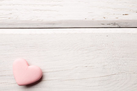 Pink heart-shaped candy on a wooden background.の写真素材