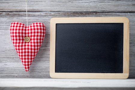 Fabric heart with a button on a white wooden background.の写真素材