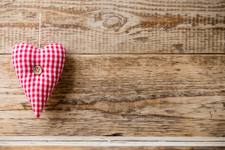 Fabric heart with a button on a wooden background.の写真素材