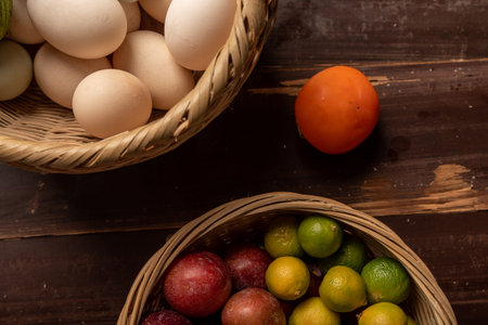 The eggs and other fruits and vegetables in the basket are on the wood grain tableの写真素材