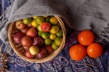 Many colors and varieties of fruit are either on the plate or scattered on the wooden table