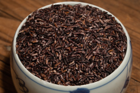 Place the black rice in the plate or bowl on the wood grain tableの写真素材