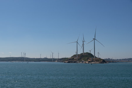 On the island in the middle of the sea, many wind turbines are installed under the blue skyの写真素材