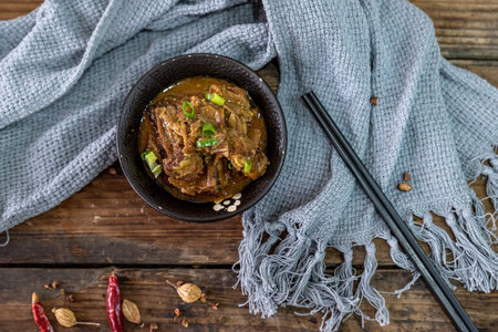 The food made of beef is in the bowl on the cloth of the wooden table