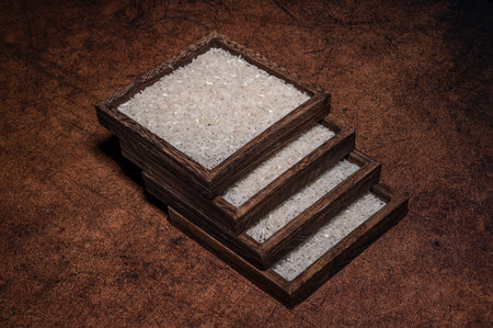 Some square containers of white rice in the dark background