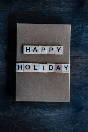 Holiday card concept with wooden blocks with letters on gift box on wooden backgroundの写真素材