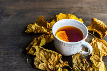 Cup of tea with lemon and dry leaves on wooden tableの写真素材