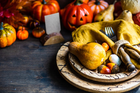 Autumnal table setting with leaves and pumpkin on wooden tableの写真素材