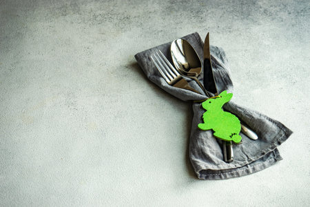 Minimalistic table setting with grey napkin and cutlery decorated with wooden bunnyの写真素材