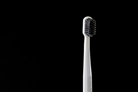 gray toothbrush with black bristles isolated on black background. copy space for text. concept of healthcare. dental care concept. selective focusの写真素材