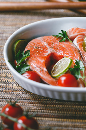 Fresh salmon steaks with lime, cherry tomatoes, parsley and olive oil. Healthy dinner or lunch concept.の写真素材