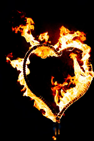 Burning heart with flames. Isolated on dark background. fire show in night. happy valentine's day card. bengal fire burning heart. space for text. wedding or valentine concept. happy new year.の写真素材