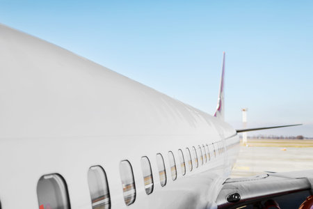Aircraft porthole - side window airplain. White heavy passenger jet engine airplane on runway at...