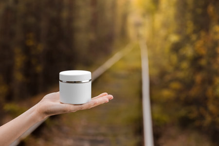 Young Female hand hold a jar of cream for face or body. organic natural skincare products on autumn...