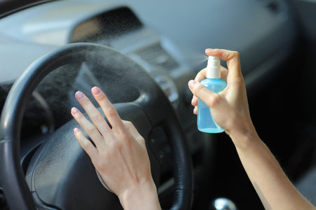 Hand of woman is spraying alcohol,disinfectant spray in car,safety,prevent infection of Covid 19...