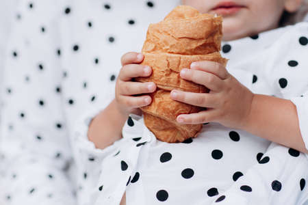 holding delicious croissant with golden crust . the baby holds a croissant in his handの写真素材