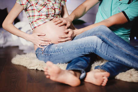 Young couple expecting baby hugging stomachの写真素材