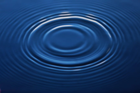 A drop of water falls into the water, making a perfect splash of drops.