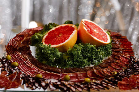 meat appetizer. Fresh sliced fruits on celebratory table. slicing sausage and grapefruit.の写真素材