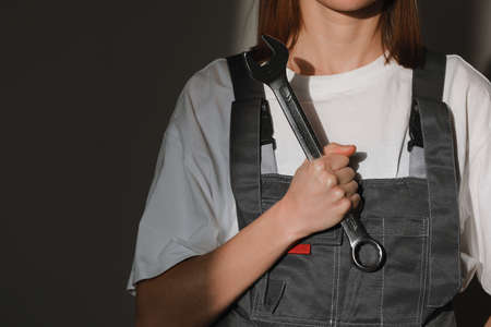 Portrait of Beautiful construction female workers wearing Protective clothes, orange helmet, hand holding wrench big screw key with sun light.の写真素材