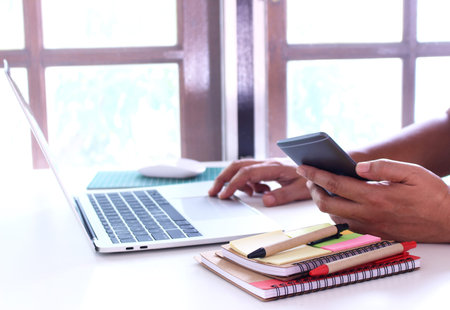 side view,business man holding smartphone .office table desk. workspace with notebook and mouse on...