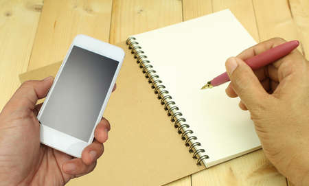 hand holding the smartphone on book backgroundの写真素材