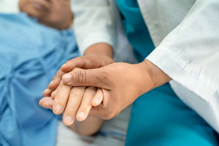 Doctor holding touching hands Asian senior or elderly old lady woman patient with love, care, helping, encourage and empathy at nursing hospital ward, healthy strong medical conceptの写真素材