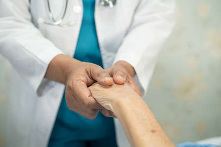 Doctor holding touching hands Asian senior or elderly old lady woman patient with love, care, helping, encourage and empathy at nursing hospital ward, healthy strong medical conceptの写真素材