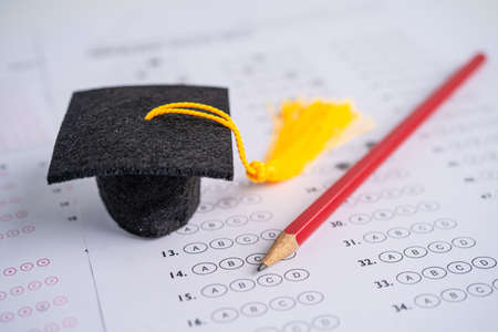 Graduation gap hat and pencil on answer sheet background, Education study testing learning teach concept.の写真素材
