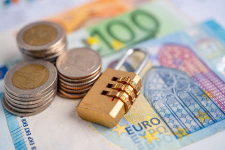 Golden security digital password lock key and coins with with Euro banknotes on graph, trade finance concept.の写真素材