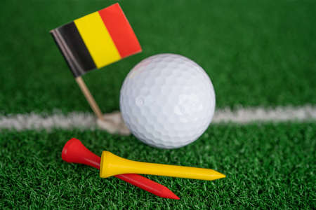 Golf ball with Germany flag and tee on green lawn or grass is most popular sport in the world.の写真素材