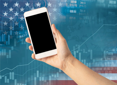 Holding mobile phone to online trade finance global business with USA America flag, stock market investmentの写真素材