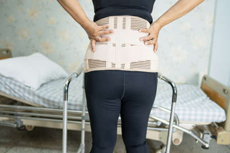 Asian lady patient wearing back pain support belt for orthopedic lumbar with walker.の写真素材