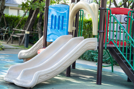 Playground for kid children having fun with colorful slide at yard activities in public park.